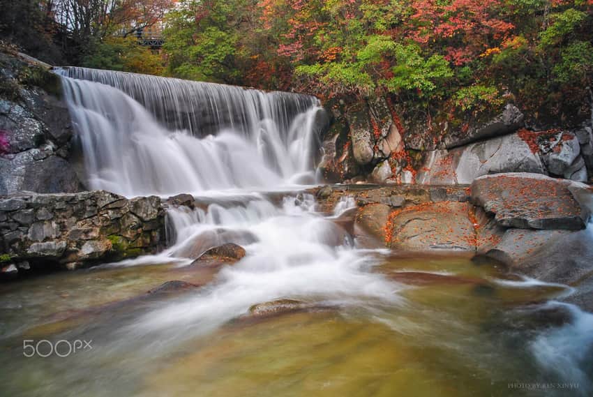 Rock cascade and red-green foliage at Guangwu Mountain
