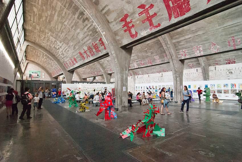 Visitors and art inside a vaulted former industrial hall at Beijing 798