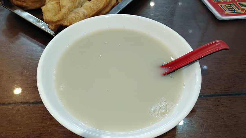 Bowl of pale douzhi with a fried dough accompaniment