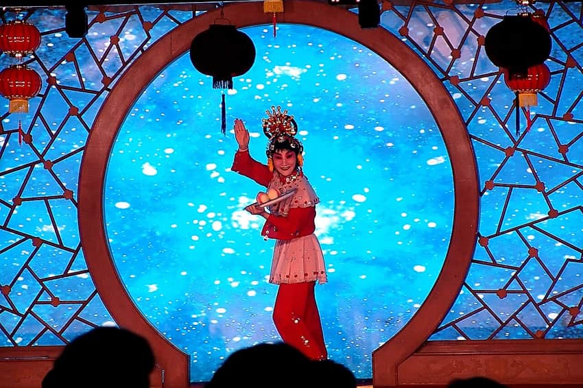 Peking-opera performer framed on a stage with audience silhouettes