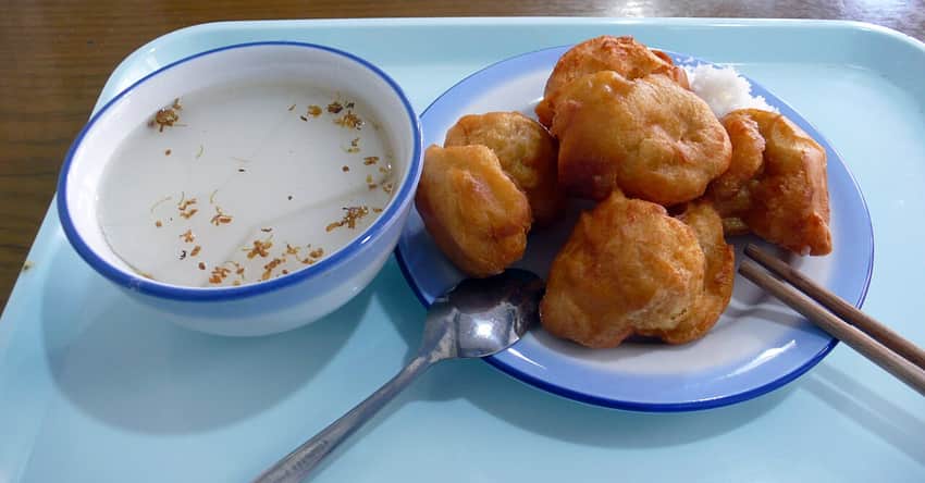 White almond-style jelly dessert beside a plate of fried cakes