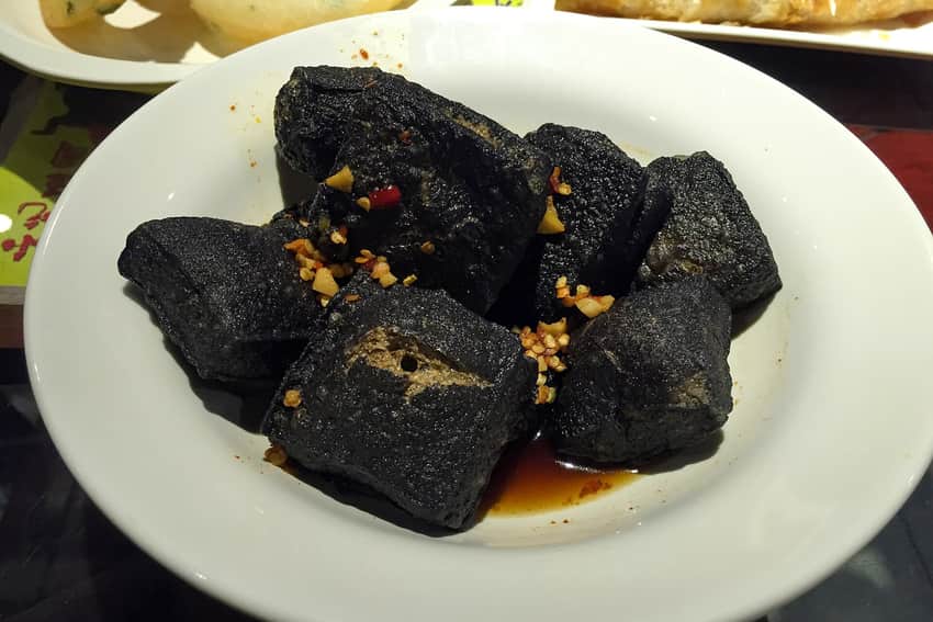 Dark fried Changsha-style stinky tofu on a white plate