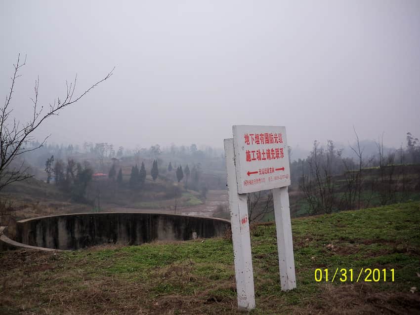 Bare orchard trees, fields, and infrastructure sign in rural Dazhu