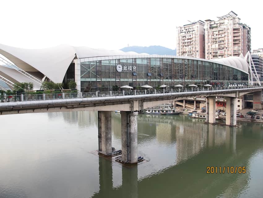 Glazed mixed-use enclosure carried above the river on a Dazhou bridge