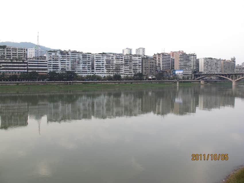 Dated riverfront blocks reflected in the Zhou River at Tongchuan