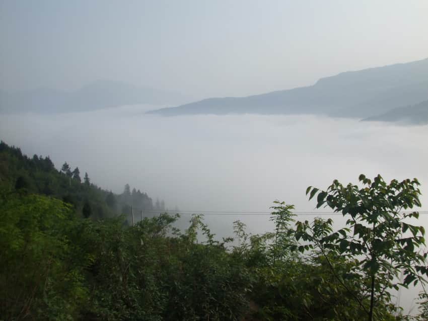 Low cloud filling valleys between layered Wanyuan mountain ridges