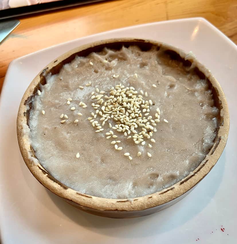 Smooth taro paste topped with sesame in a shallow earthenware bowl