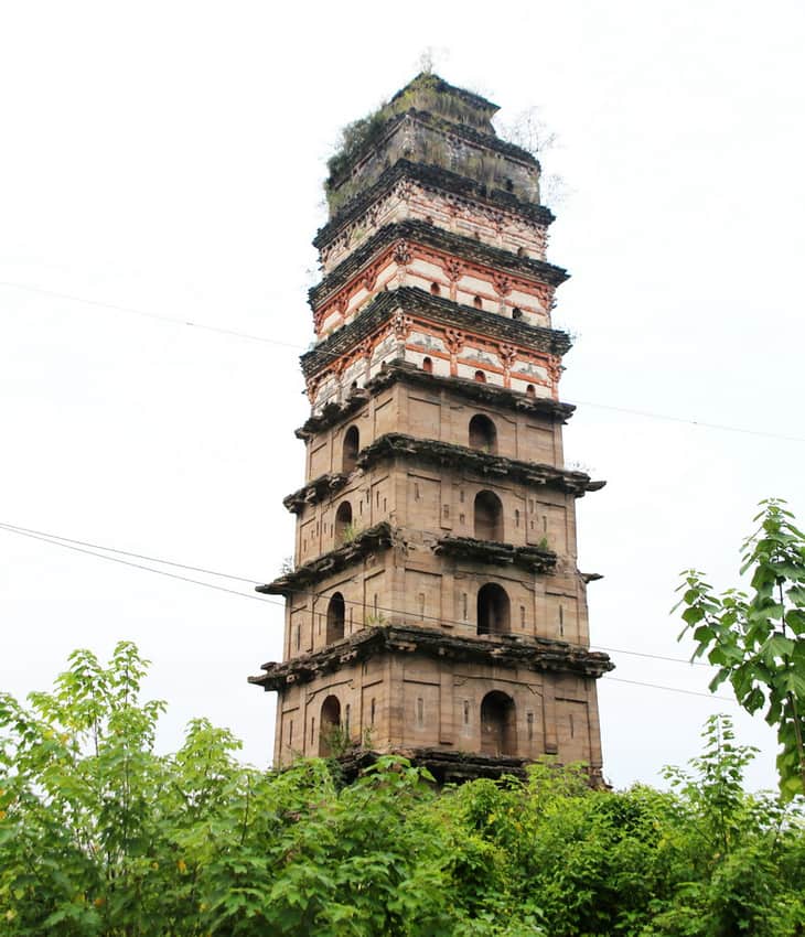 Weathered Guang'an White Pagoda rising above vegetation