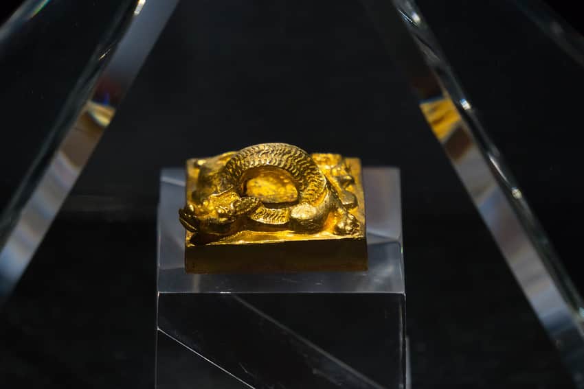 Gold seal with a coiled dragon knob in a museum case