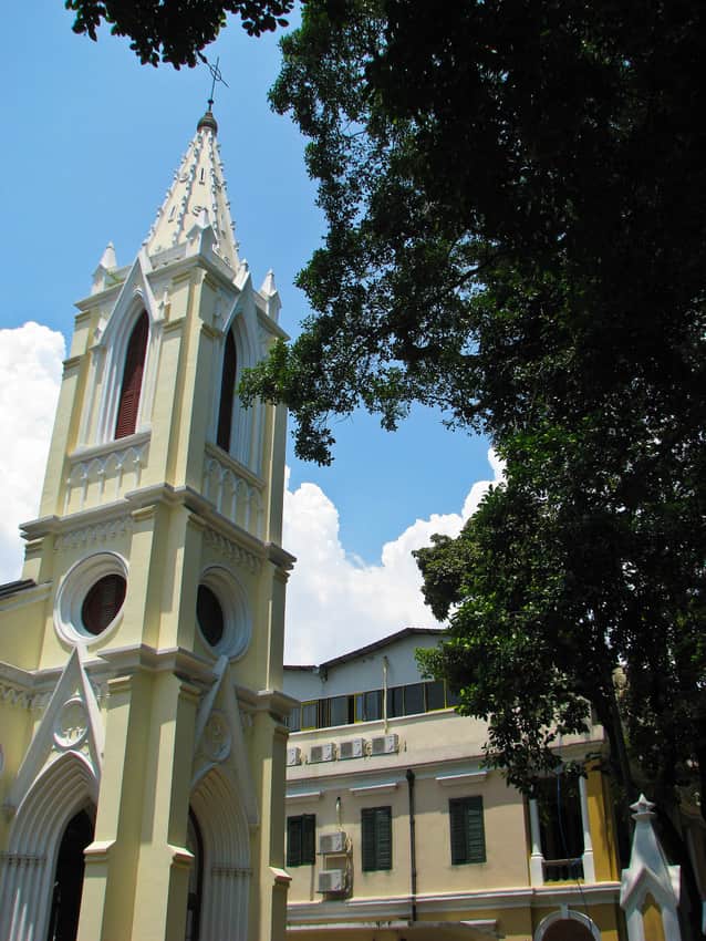 Pale church tower framed by trees on Shamian