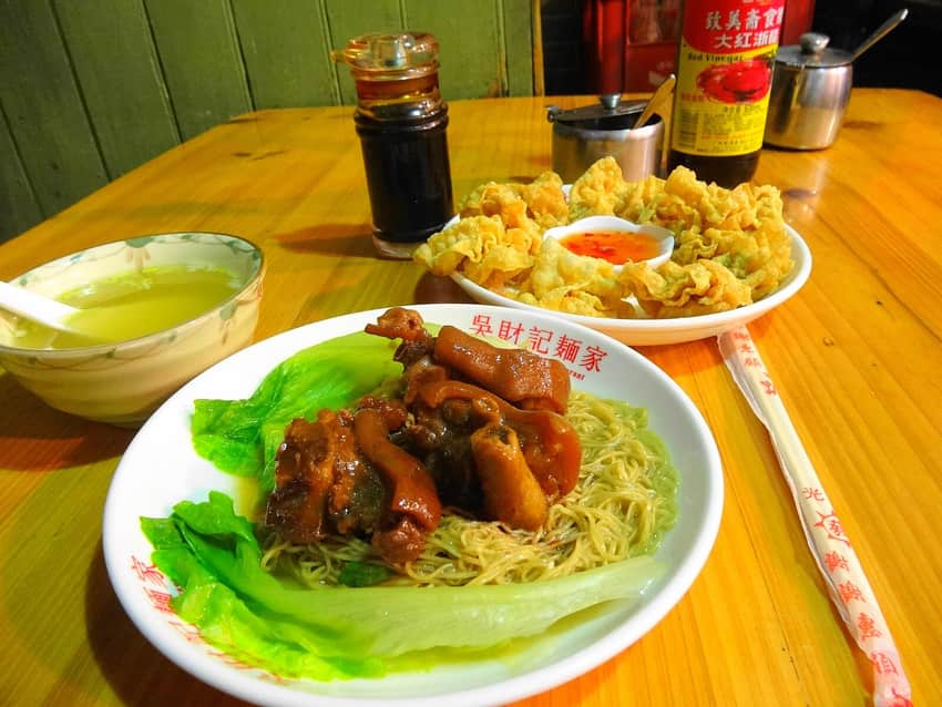 Lo mein, fried wontons, broth and condiments at a noodle shop
