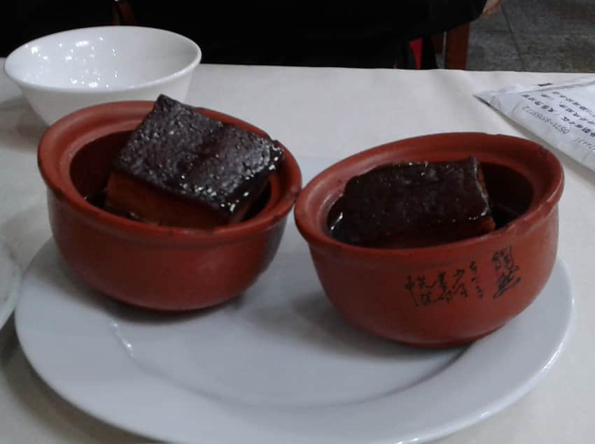 Two clay bowls containing glossy cubes of Dongpo pork in dark sauce