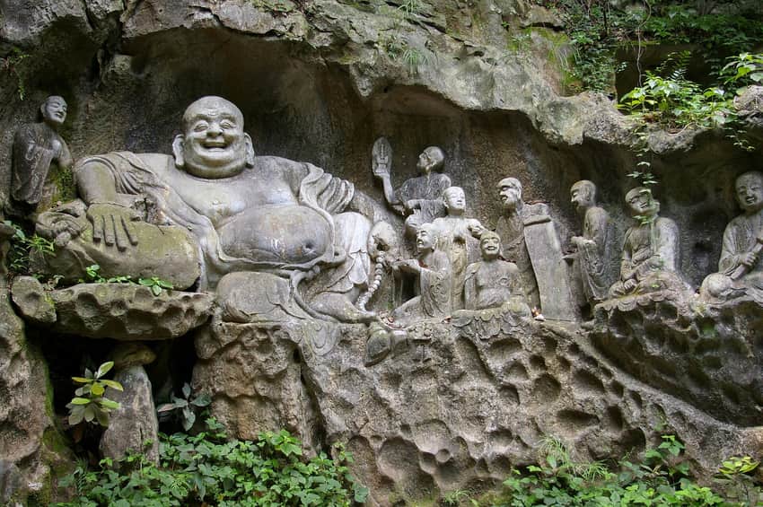 Close view of Buddhist figures carved into mossy rock at Feilai Feng