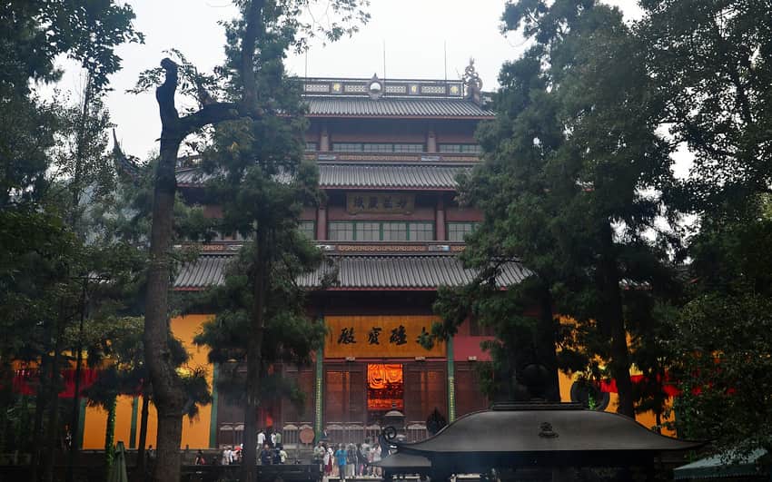 Mahavira Hall and yellow walls of Lingyin Temple seen through mature trees