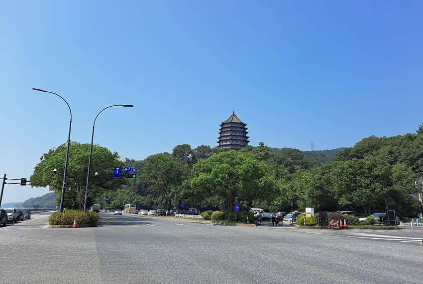 Distant Liuhe Pagoda above a wooded hill and modern roadway