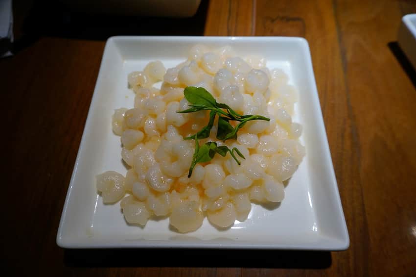 Pale Longjing prawns on a square plate with green tea leaves
