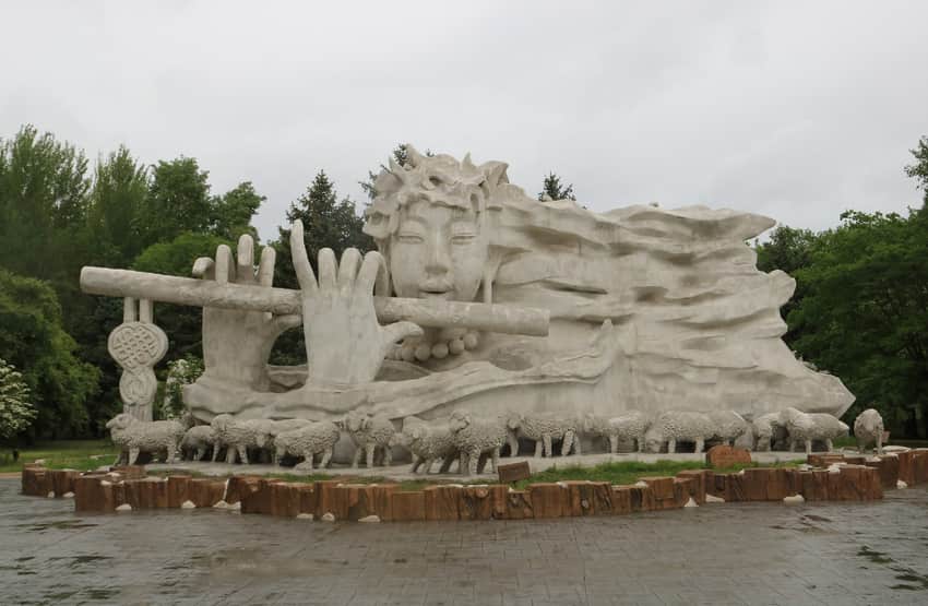Large flute-player sculpture and sheep figures on Sun Island