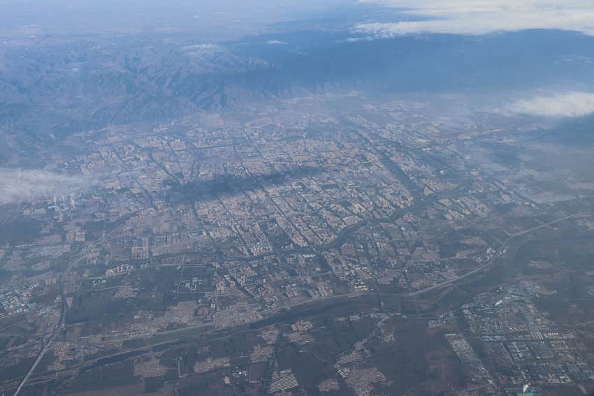 Oblique aerial view of Hohhot's street grid, fields and mountains