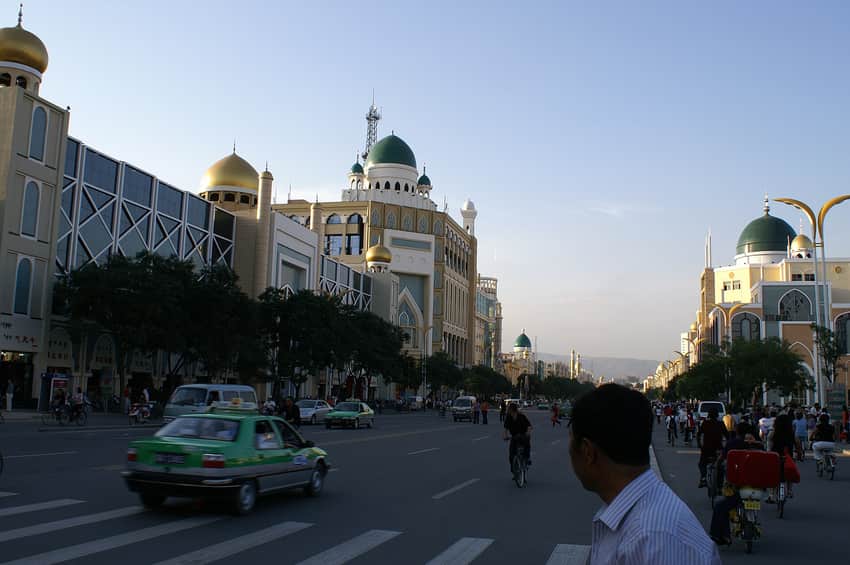 Dated boulevard with dome-shaped facades, cars, cyclists and pedestrians