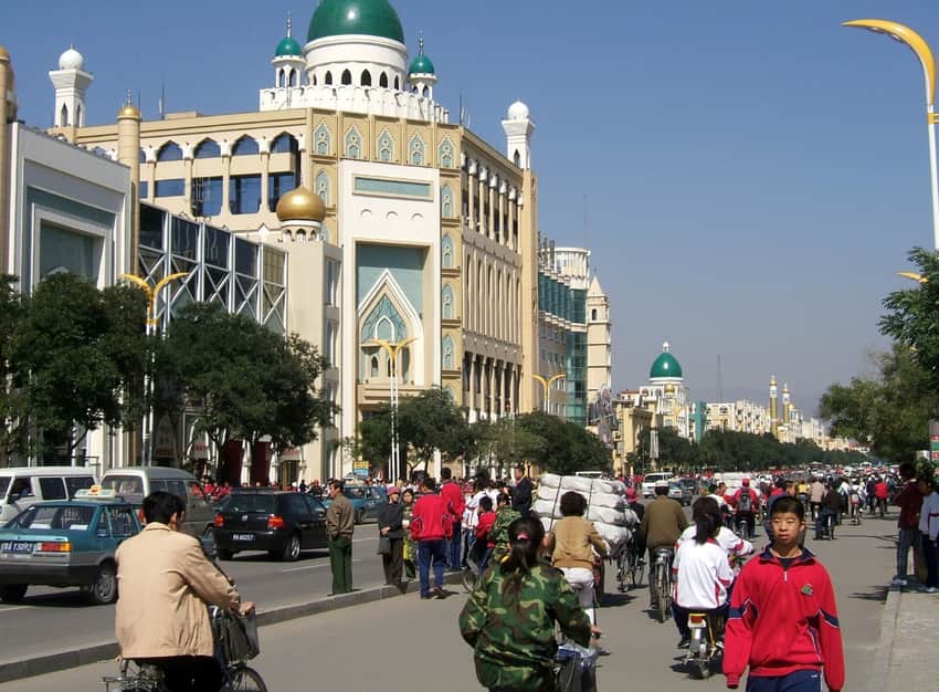 Dated commercial street with dome-shaped facades, bicycles, cars and pedestrians