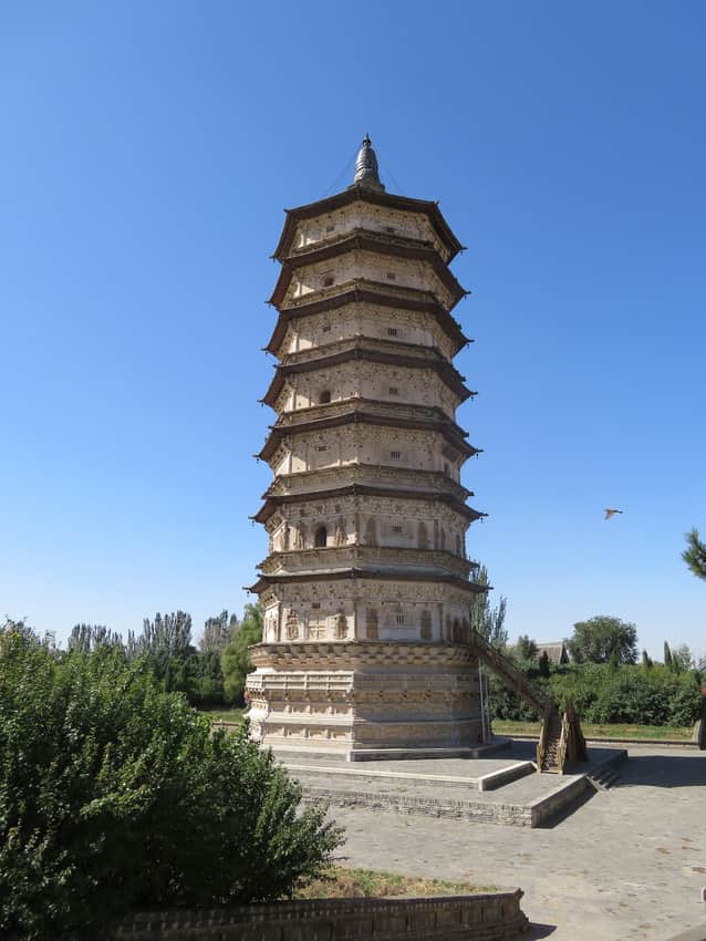 Octagonal multi-storey White Pagoda with trees and modern visitor stairs