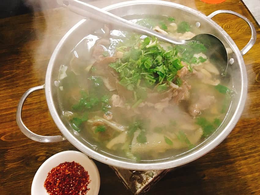 Steaming pot of qiaojiao beef with herbs and chile dip
