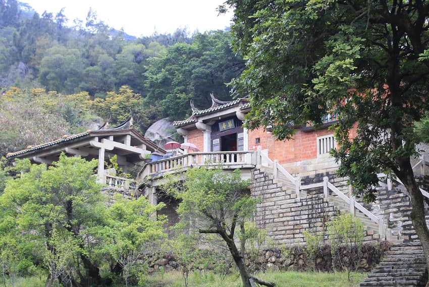 Red-brick exterior of Cao'an on a wooded rocky slope
