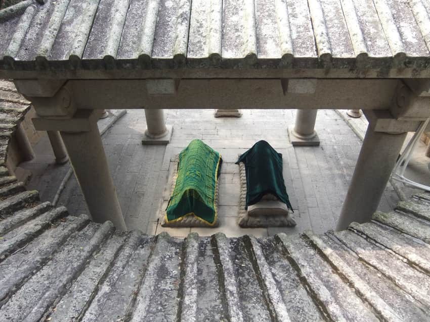 Two cloth-draped tombs viewed through a stone pavilion at Lingshan Islamic Cemetery