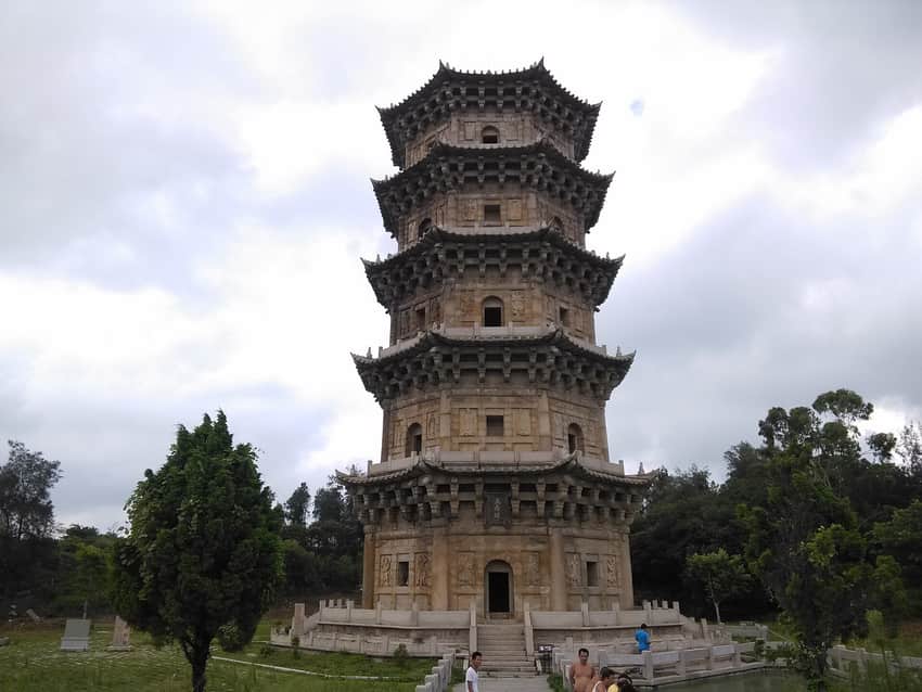 Tall stone Liusheng Pagoda under cloudy sky with visitors at the base