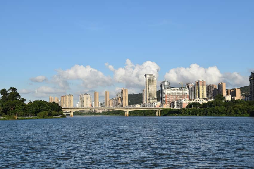 Modern Nan'an cityscape across the Xixi river with bridge and forested hills