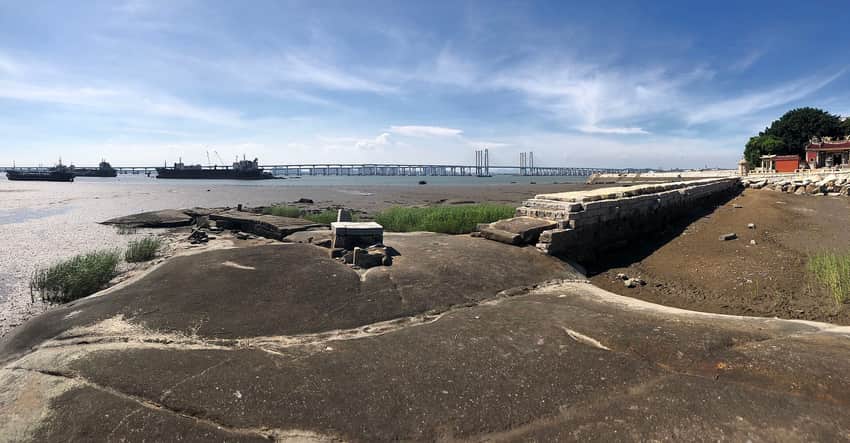 Stone wharf, tidal flats, cargo vessels and modern bridge at Shihu harbor