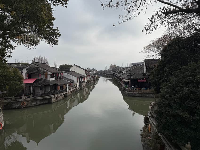 Overcast canal view through Fengjing with tiled houses and riverside walkways