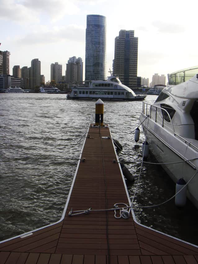 Passenger vessel crossing the Huangpu beyond a pontoon and moored boat