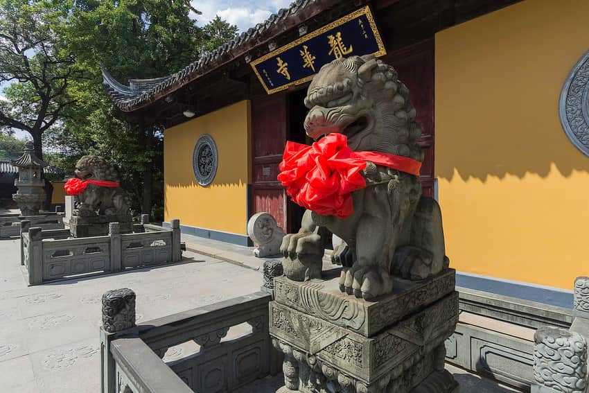 Longhua Temple entrance with yellow walls, tiled eaves and stone guardian lions