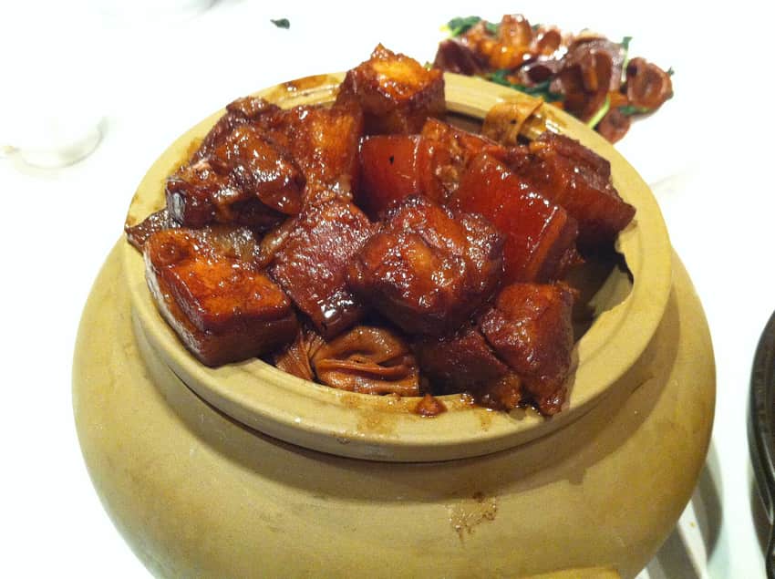 Glossy red-braised pork pieces in a clay-colored serving pot