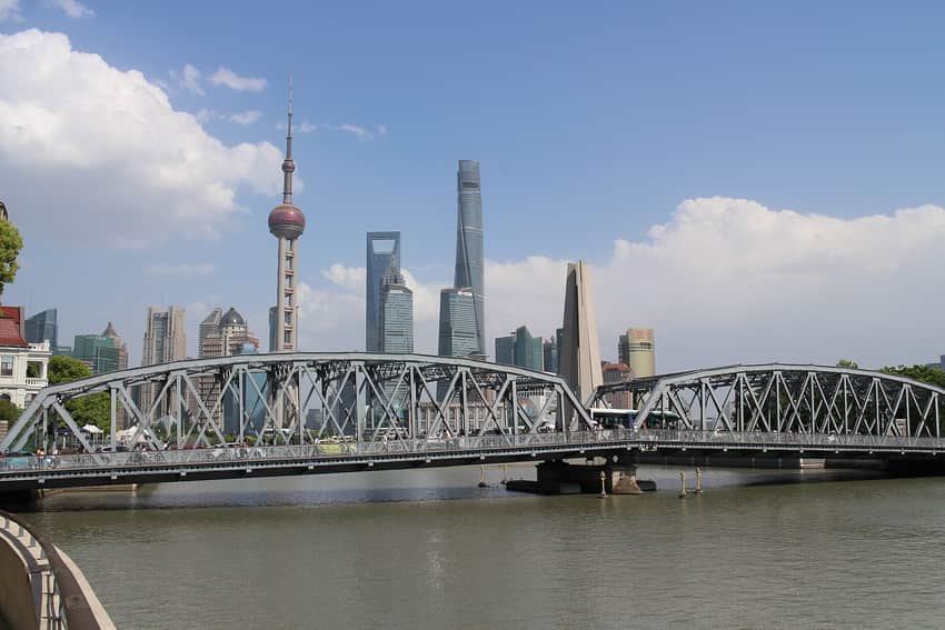 Steel-truss Waibaidu Bridge with pedestrians, a bus and the Pudong skyline