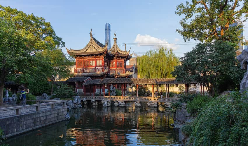 Traditional halls, corridor, pond and rocks at Yu Garden with skyscrapers behind