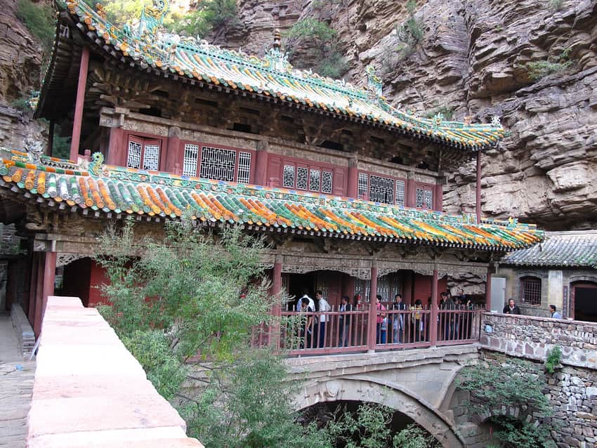 Temple structure spanning a steep wooded cleft at Mount Cangyan