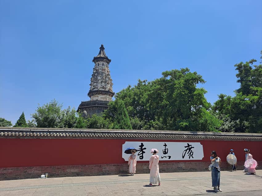 Hua Pagoda rising behind trees and enclosure walls with visitors in Zhengding