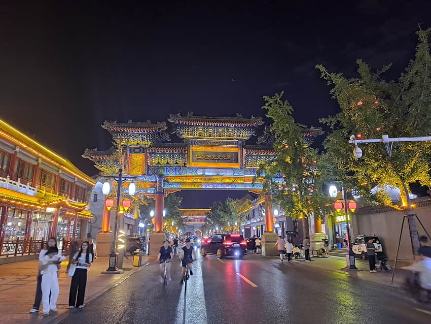 Cars, pedestrians and illuminated gateway on a Zhengding street at night