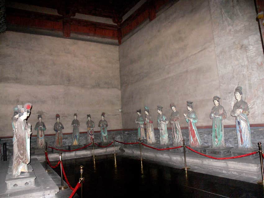 Painted maid sculptures behind a visitor barrier inside Jinci