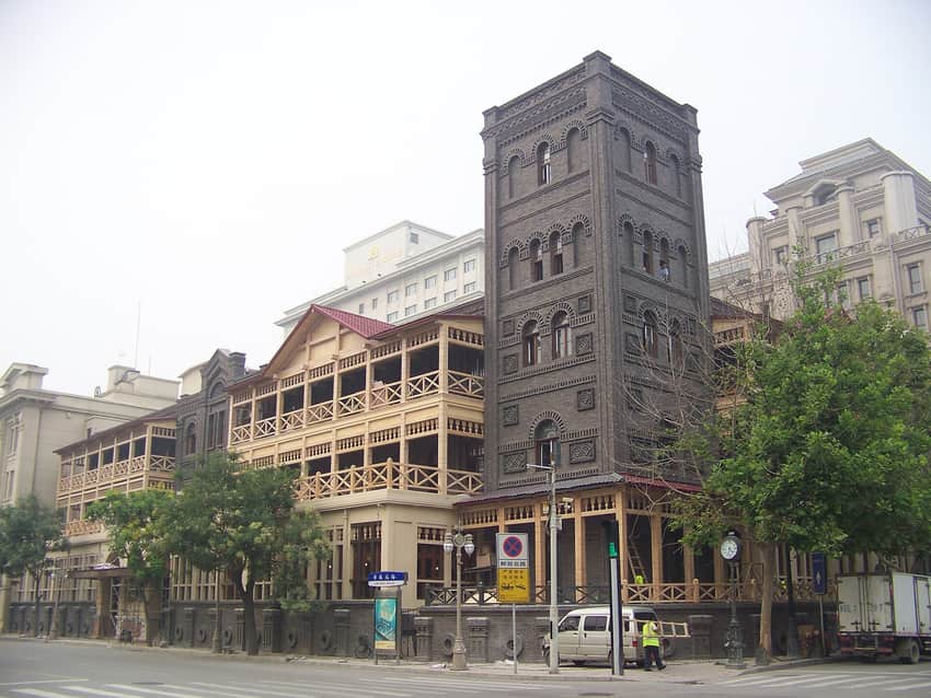 Historic Astor Hotel facade with later wing, road signs and vehicles in Tianjin