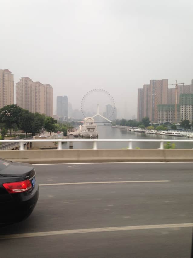 Tianjin Eye behind road barriers, traffic and high-rises in a dated view