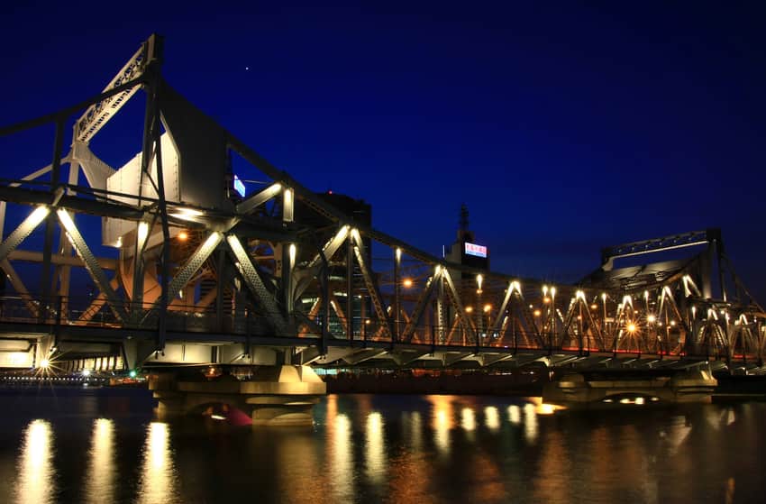 Illuminated riveted trusses of Jiefang Bridge reflected in the Hai River