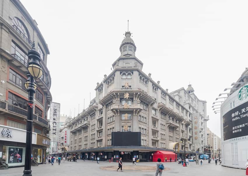 Corner facade, shops and pedestrians at Tianjin Quanye Department Store in 2019