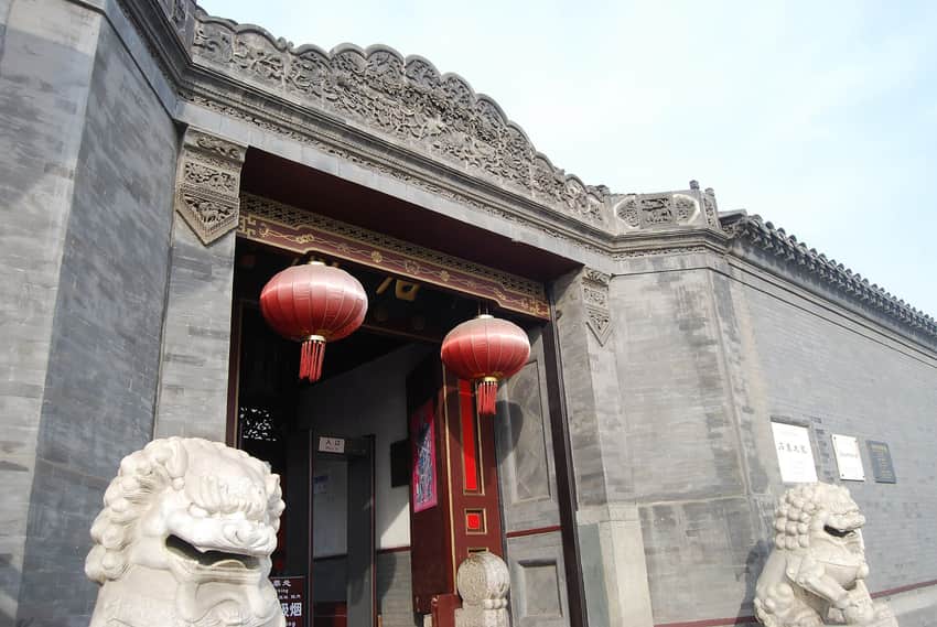 Grey-brick carved entrance, lanterns and stone lions at Shi Family Grand Courtyard