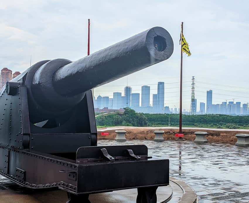 Artillery display at the Taku Fort site with modern Binhai skyline beyond