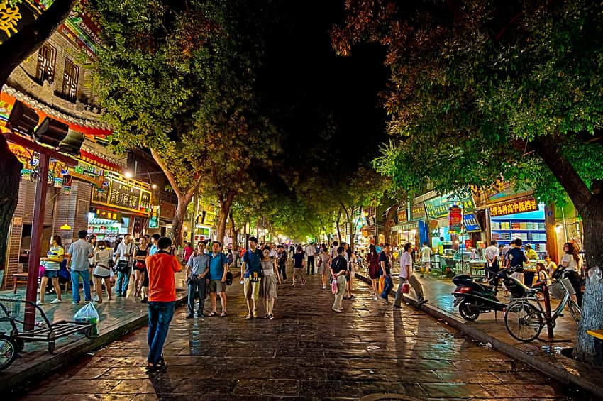 Busy illuminated night street with shops and pedestrians in Xi'an's Muslim Quarter