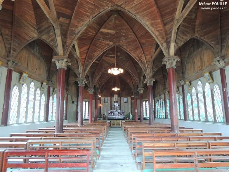 Timber columns, pointed arches, pews, and altar inside Dengchigou church
