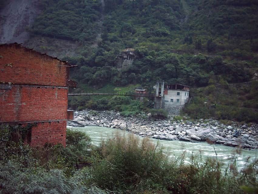 Narrow chain bridge crossing rocky water in Shimian